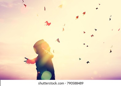 Freedom feel good and travel adventure concept. Copy space of silhouette man rising hands on sunset sky double exposure colorful bokeh and bird fly background. Vintage tone filter effect color style.