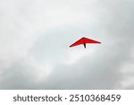 The freedom of hang gliding - a red kite against a cloudy sky