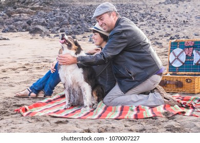 Freedom And Leisure Pic Nic Activity On The Beach For An Alternative Family Group Of Friends Two Person And A Nice Dog. Everybody Have Fun Outdoor In Vacation