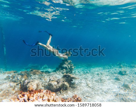 Freedom lifestyle and aquatic underwater life on Raja Ampat island of New Guinea, active woman in swim mask and flippers enjoying summer scuba diving in blue ocean with beautiful coral reef