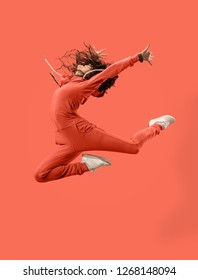 Freedom in moving. Mid-air shot of pretty happy young woman jumping and gesturing against coral studio background. Runnin girl in motion or movement. Human emotions and facial expressions concept - Shutterstock ID 1268148094