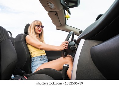 Freedom Of The Open Road. Side View Of Joyful Young Woman Relaxing On The Front Seat And Driving Convertible. Beautiful Sexy Blonde Behind The Wheel. Female Driver.