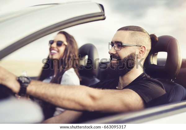 Freedom of the open road.Young Couple Driving\
Along Country Road In Open Top\
Car.