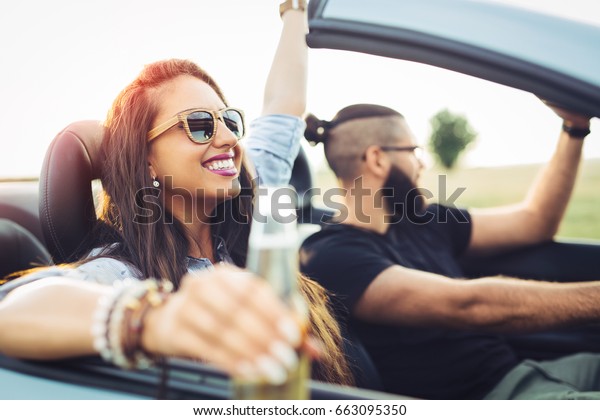 Freedom of the open road.Young Couple Driving\
Along Country Road In Open Top\
Car.