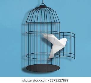 Freedom. Paper bird flying out of broken cage on light blue background