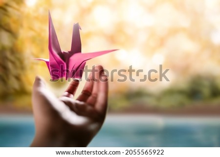 Freedom, Peace, Imagination,Mental Health and Creativity Concept. Paper Crane Origami Bird Levitating over an opened Hand Gesture. Release, Peaceful, Enjoying and Life Philosophy