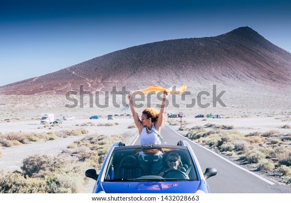 Freedom and travel concept for\
independent adult caucasian women together with convertible car -\
people traveling and enjoying tie friendship - drive and road\
concept