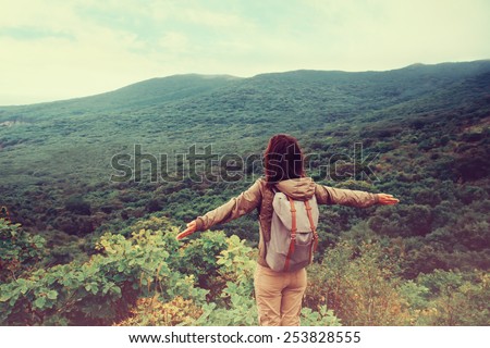 Freedom traveler woman standing with raised arms and enjoying a beautiful nature. Image with instagram filter