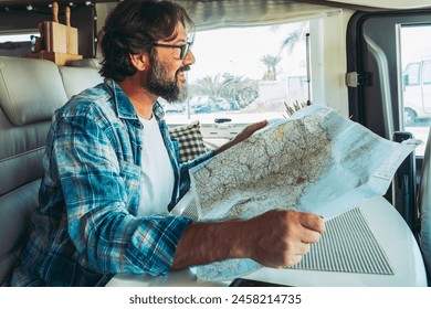 Freedom and vehicle vanlife licestyle. One happy mid age man smiling and planning roads trip on map guide sitting inside a camper van motor home. Alternative cozy nomadic home and life. Vacation. - Powered by Shutterstock