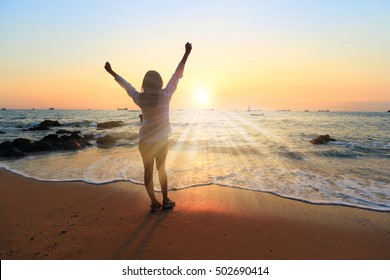 Freedom winning woman cheering at sunset beach. Success concept with female adult from the back arms up at the sky looking at the ocean feeling free and successful. Achievement of her life. - Powered by Shutterstock