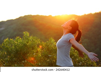 Freedom woman open arms at sunrise mountain peak wellness concept