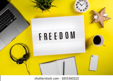 Freedom Word On Lightbox On Modern Yellow Office Desktop With Laptop, Smartphone, Coffee Mug, Notebook. Fundamental Human Rights, Political Freedoms, Freedom Of Speech, Liberation From Slavery Concept