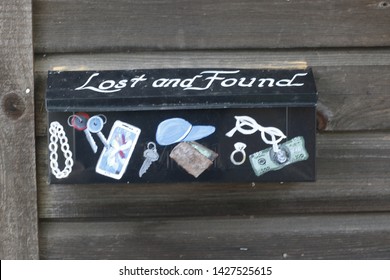 Freehold, NJ / USA - June 17, 2019: Lost And Found Box On The Side Of A Wooden Shed Decorated With Symbols Designating Things That Might Be Found And Left.