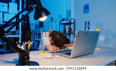 Freelance Asia exhausted lady hard work sleeping at new normal home office. Working from house overload at night, Remotely, self isolation, social distancing, quarantine for corona virus prevention.