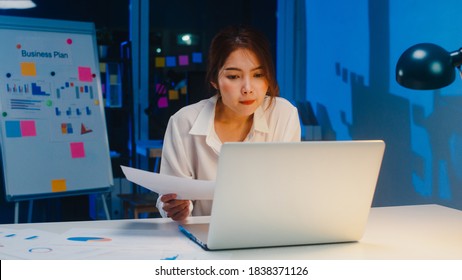 Freelance Asia women using laptop hard work in living room at house. Working from home overload at night, remotely work, self isolation, social distancing, quarantine for corona virus prevention. - Shutterstock ID 1838371126