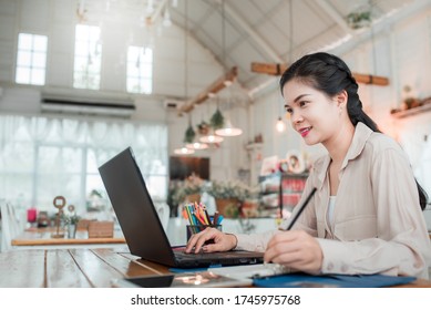 A freelance Asian young woman working using laptop computer in a home freelance woman using a laptop sitting at a wooden table - Shutterstock ID 1745975768