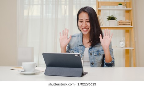 Freelance business women casual wear using tablet working call video conference with customer in workplace in living room at home. Happy young Asian girl relax sitting on desk do job in internet. - Powered by Shutterstock