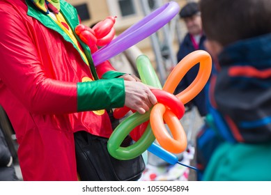 A freelance clown creating balloon animals and different shapes at outdoor festival in city centre. School bag, angel wings, butterflies and dogs made of balloons. Concept of entertainment, birthdays - Shutterstock ID 1055045894