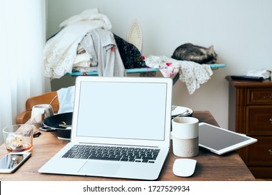 Freelance Desk with laptop in mess at home apartment. Quarantine, self-isolation, sociophobia. Concept of abandoned household