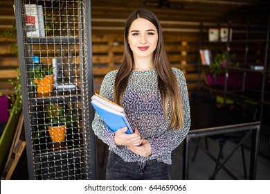 Freelance developer or designer with notebooks and papers standing at office