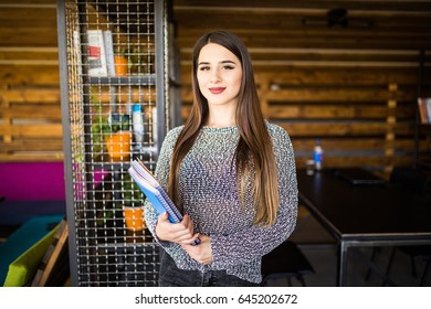 Freelance developer or designer with notebooks and papers standing at office
