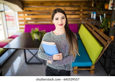 Freelance developer or designer with notebooks and papers standing at office