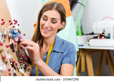 Freelance - jewelry designer working on a draft, different pieces of jewelry hanging in front - Powered by Shutterstock