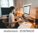 Freelance lifestyles working at home office concept. Asian man using computer productive time manage. Cozy room warming lighting ambient. Digital nomad with modern technology.