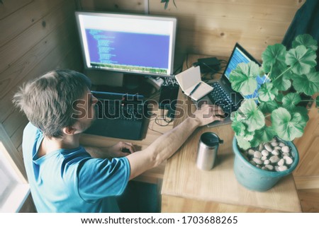 freelance programmer with two laptops working from home in quarantine, concept of self-isolated lifestyle workspace or workplace, home office, top view from above with bokeh effect