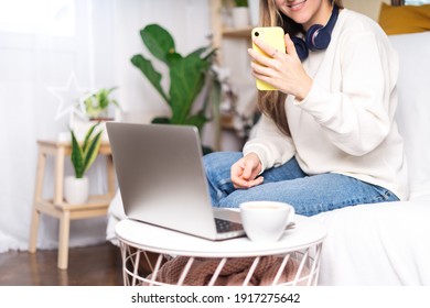 Freelance woman with headphones and laptop, taking selfie at mobile phone. Sitting on the couch, online shopping. Happy girl woking from home office. Distance learning online education and work.
