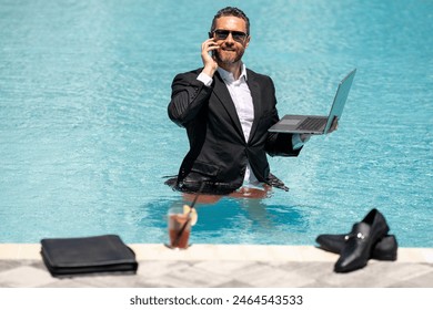 Freelance work, distance online work, e-working. Summer business. Business man in suit remote working on laptop in pool. Business man working online on laptop in summer swimming pool water. - Powered by Shutterstock