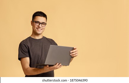 Freelance and work online at home in self-isolation during COVID-19 lockdown. Happy millennial handsome man with glasses hold laptop and surfing in internet, isolated on light background, empty space