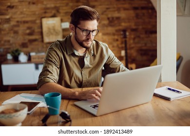 Freelance worker using laptop and typing an e-mail while working at home. 