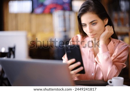 Freelance worker using multiple devices and checking phone in a bar