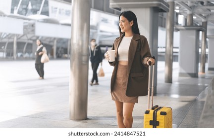 Freelance young adult asian woman walking with travel luggage and coffee cup for business trip. Beautiful smile face long hair at station platform on day. Urban people lifestyles. - Powered by Shutterstock