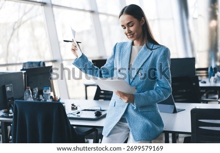 Freelancer analyzes documents with subtle smile, expressing confident ownership, tech-supported clarity and self-assured decision-making in professional role
