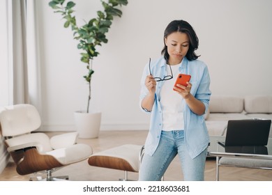 Freelancer, Employee Or Businesswoman Has Online Discussion With Colleagues In Chat. Lady Is Texting On Phone. Young Spanish Woman Working At Home Office. Gadget Using, Remote Work Through Internet.