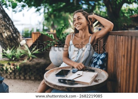 Freelancer enjoying mindful moment while seated outdoors, smiling and looking away from screen, reflecting the emotional side of technology use and personal space in mobile freelance routine.