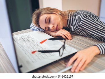 freelancer girl was tired and fell asleep at work at a desk near a white notebook. Break at work, quiet hour