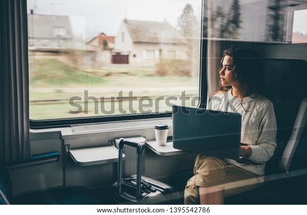 Freelancer girl working with laptop\
in the train, business travel or technology concept.\

