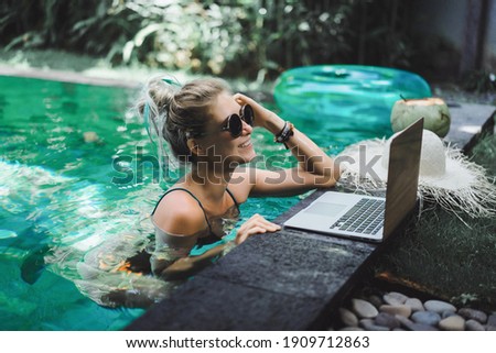 Freelancer girl working on vacation. 
Young woman with laptop works while sitting on a sun lounger. Work from anywhere, freelance.