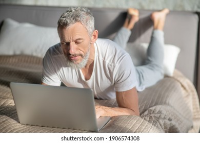 Freelancer. A grey-haired man using a computer while staying at home