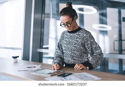 Freelancer interacting with tablet while standing, illustrating focused digital process, multitool control and individual rhythm of remote tech-enabled career.