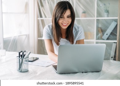 Freelancer Lifestyle. Home Relocation. Remote Job. Virtual Office. Happy Satisfied Woman Working Online Using Laptop In New Modern Light Room With Covered Furniture.