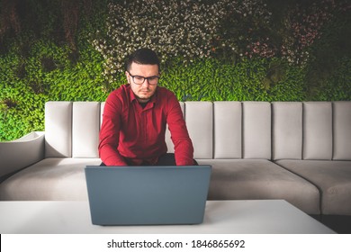 Freelancer man with face mask in red shirt with glasses working on laptop in coffee shop, remote work - Powered by Shutterstock