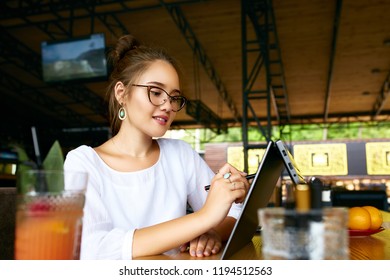 Freelancer mixed race woman hand pointing with stylus on convertible laptop screen in tent mode. Asian caucasian girl using 2 in 1 notebook with touchscreen for drawing and work on design project. - Shutterstock ID 1194512563