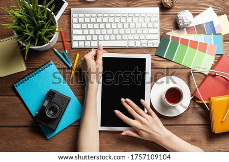 Freelancer sitting at desk and tablet computer. Business occupation and innovation technology. Home office workspace with camera and cup of coffee. Woman blogger or columnist work at wooden desk.