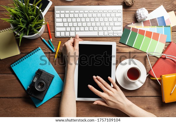 Freelancer sitting at desk and tablet computer.\
Business occupation and innovation technology. Home office\
workspace with camera and cup of coffee. Woman blogger or columnist\
work at wooden desk.