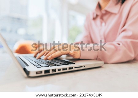 A freelancer is sitting in a café, using a laptop to reply to clients' inquiries and requests.