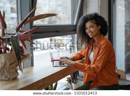 Freelancer typing on keyboard using laptop computer. Portrait of cheerful woman copywriter working from home. Smiling African American student studying, learning language, exam preparation